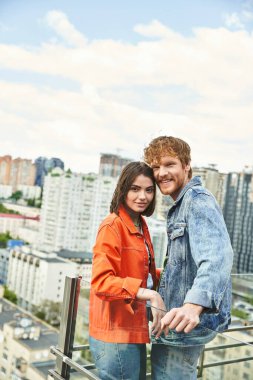 A man and a woman stand confidently atop a skyscraper, overlooking the city below with a sense of awe and accomplishment clipart