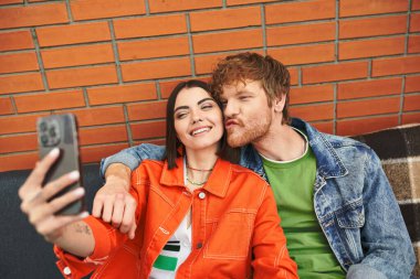 Bir adam ve kadın gülümsüyor, cep telefonu tutuyor, mutlu bir bağ ve aşk anında selfie çekiyorlar.
