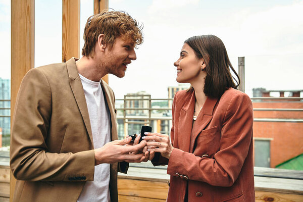 A man on one knee extends an engagement ring to a woman, their eyes locked in excitement.
