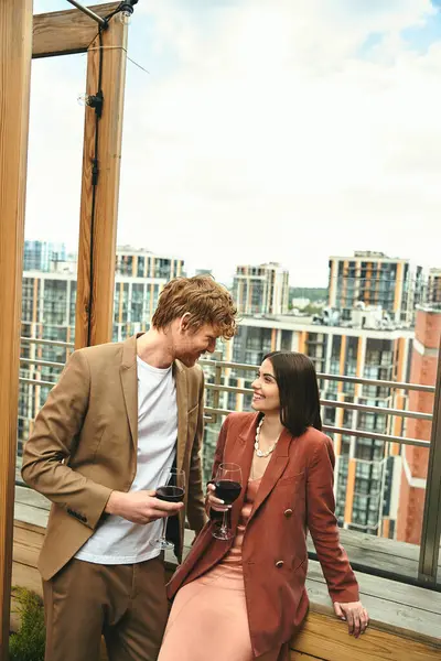 stock image A man in a sharp suit stands next to a woman holding a glass of wine, exuding sophistication and refinement at a chic event