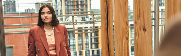 Женщина грациозно стоит перед окном, ее силуэт освещается мягким, золотым светом, проникающим через стекло