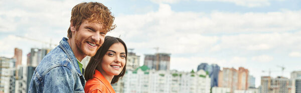 A man and a woman stand before a sprawling city skyline, gazing out at the towering buildings in awe and wonder