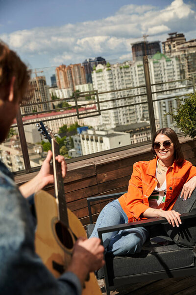 A woman sits on a bench, serenading the evening with her guitar melodies under the fading light of dusk