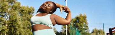 Spor kıyafetli bir Afrikalı Amerikalı kadın kollarını açık havada açıyor, vücudunun pozitifliğini kucaklıyor..