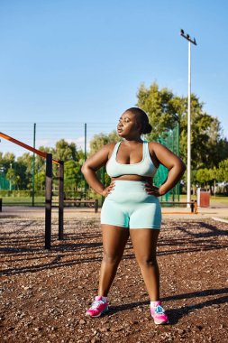 Spor giyim sektöründe Afro-Amerikalı bir kadın oyun parkının önünde kendine güvenerek duruyor, pozitifliği ve gücü somutlaştırıyor..