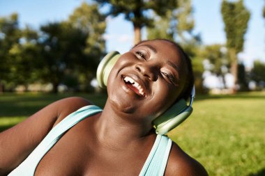 Spor giyimli ve kulaklıklı Afro-Amerikalı bir kadın doğanın tadını çıkarıyor..