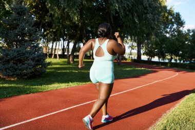 Spor giyim sektöründe Afro-Amerikalı bir kadın kırmızı pist boyunca koşuyor, vücut pozitifliği ve atletizm gösteriyor..