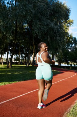 Vücut pozitifliği olan Afro-Amerikan bir kadın spor giyim sektöründe koşuyor, zarafet ve güç gösterisi yapıyor..