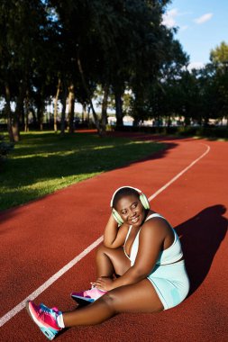 Tenis kortunda oturan Afro-Amerikalı bir kadın.
