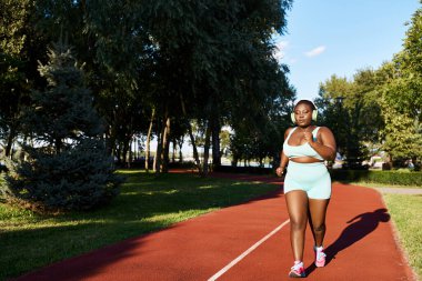 Spor giyim sektöründe Afro-Amerikalı bir kadın canlı kırmızı bir pistte azimle koşuyor. Güç ve atletizmi simgeliyor..
