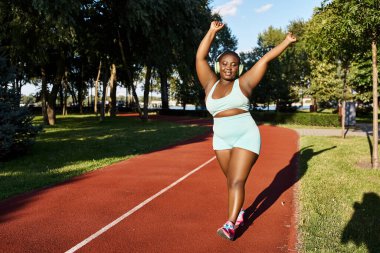 An African American woman in sportswear runs on a track with trees in the background, showcasing her body-positive and curvy form. clipart