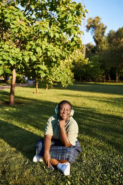 stock image A plus size African American woman in casual clothing sitting peacefully on the grass outdoors on a sunny summer day.