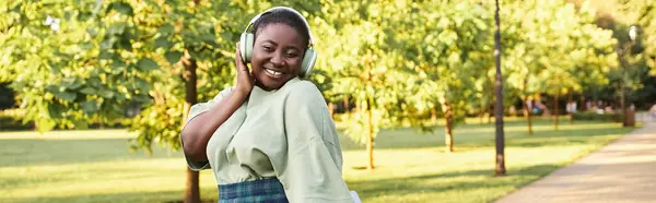 stock image Plus-size African American woman in casual attire, showcasing body positivity, listening to music on headphones