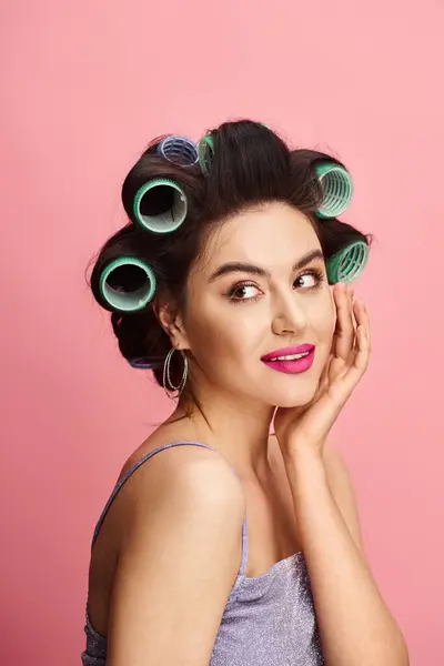 stock image A stylish woman with curlers in her hair represents natural beauty on a vibrant backdrop.