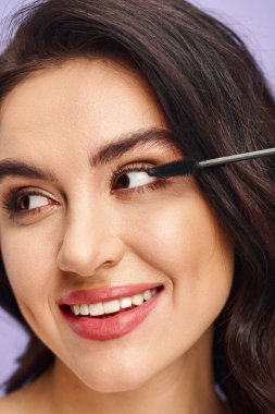 A woman delicately applying mascara with a brush to enhance her eye. clipart