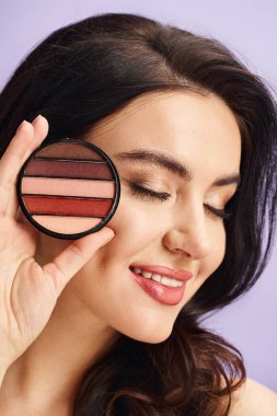 A woman with natural beauty holds a palette and applies makeup. clipart