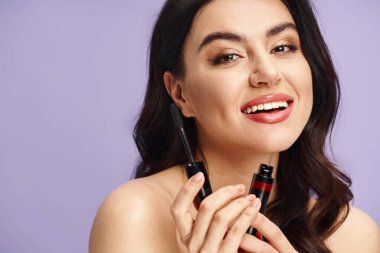 Bir kadın rimel tutarken gülümsüyor..