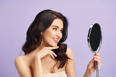 Woman in strapless dress gazes at herself in mirror while applying makeup. clipart