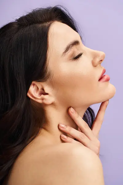 stock image A captivating woman with her hand elegantly positioned on her neck.