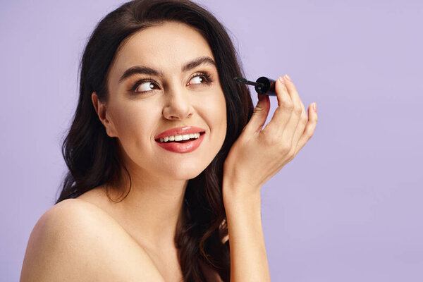 A woman with natural beauty holds a mascara in her hand.