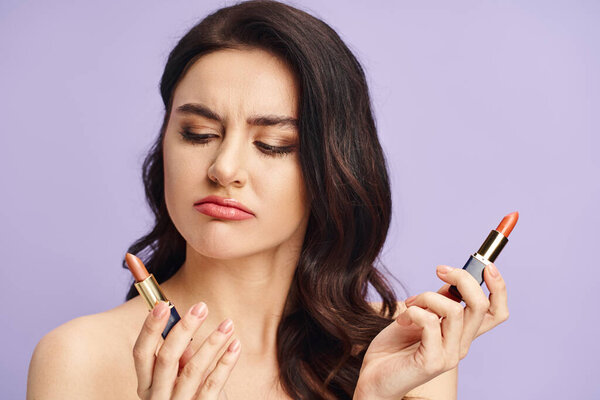 A woman with natural beauty holds two lipsticks, choosing shades.
