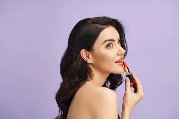 stock image A woman gracefully holds a lipstick in her hand, enhancing her natural beauty.