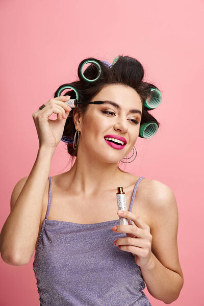 Stylish woman holding maskara with curlers in her hair.