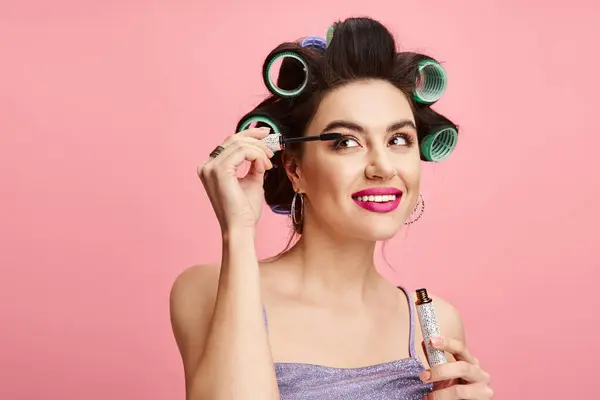 stock image Stylish woman with curlers in hair applying makeup.