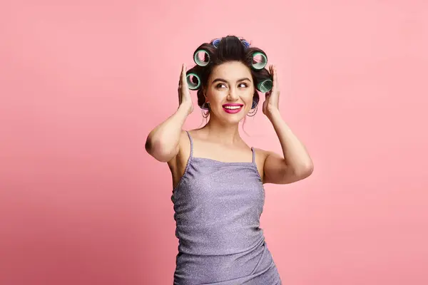 stock image Stylish woman in dress playfully balancing green hair rollers on her head.