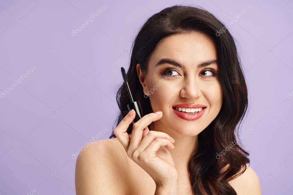 A woman with natural beauty holds mascara to her face.