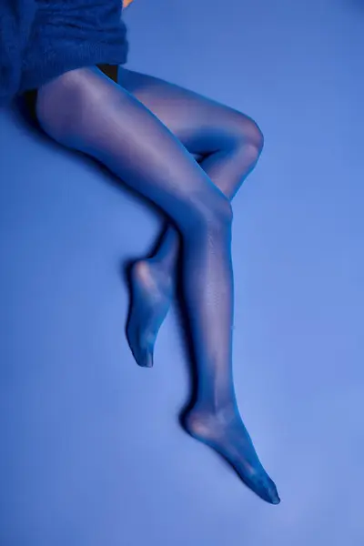 若い女性は スタジオで背景にポーズを打ちながら 鮮やかな青いストッキングで彼女の足を示しています — ストック写真