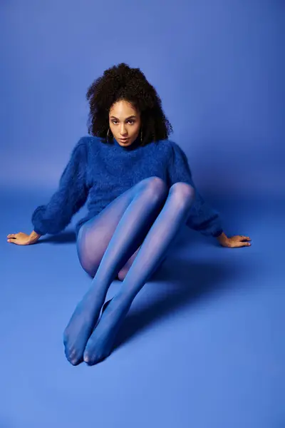 Young Woman Vibrant Tights Sweater Sits Floor Studio Blue Background — Stockfoto