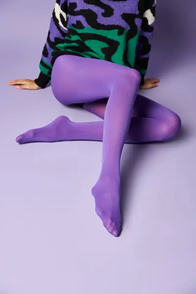 Young Woman Vibrant Tights Sweater Sitting Cross Legged Purple Background Stock Fotografie