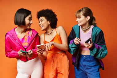 Farklı etnik kökenlere sahip üç kadın birlikte cep telefonu ekranına dikkatle bakıyor..