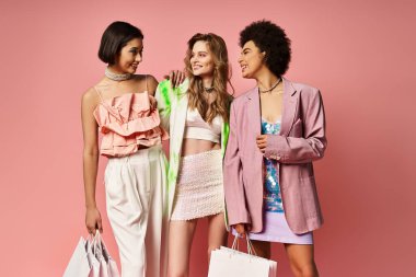 Three women of diverse backgrounds stand together, clutching shopping bags against a pink studio backdrop. clipart