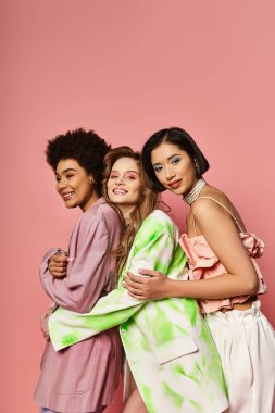 Farklı etnik kökenlere sahip bir grup kadın pembe bir arkaplan önünde bir araya gelerek birlik ve çeşitlilik sergiliyor..