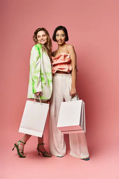 2人の白人と1人のアフリカ系アメリカ人女性がピンクの背景にショッピングバッグを持って立っています — ストック写真