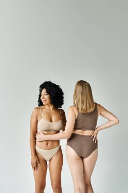 Two beautiful women in cozy pastel underwear standing next to each other. clipart