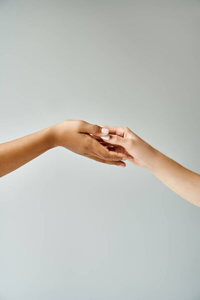 Two beautiful diverse women reaching out towards each other with their hands.