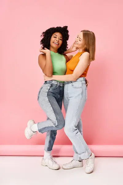 Two Women Casual Attire Embrace Smiling Pink Backdrop — Stock Photo, Image