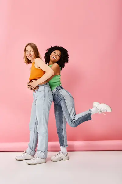 Две Молодые Девушки Повседневной Одежде Обнимаются Перед Розовой Стеной — стоковое фото