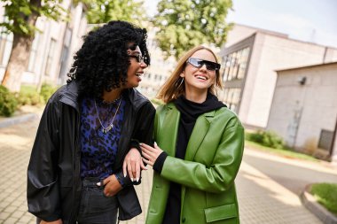 Two beautiful, diverse women stand together in cozy casual attire, sharing a moment of connection and friendship. clipart