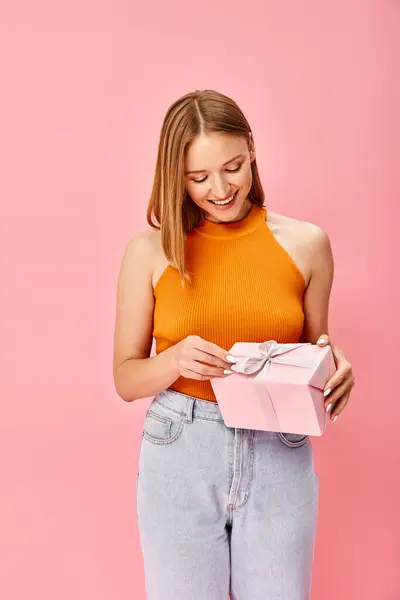 Een Vrouw Een Oranje Top Heeft Een Roze Geschenkdoos Die Stockafbeelding