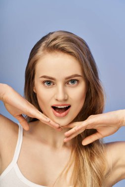 A young, blonde woman passionately creates a heart shape with her hands in a studio setting. clipart