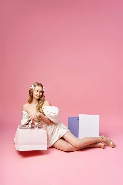 Young Blonde Woman Sits Gracefully Ground Holding Shopping Bag Embodying — Stock Photo, Image
