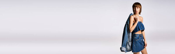 Молодая женщина с короткими волосами стоит в синем платье, лицом к камере в созерцательной позе.