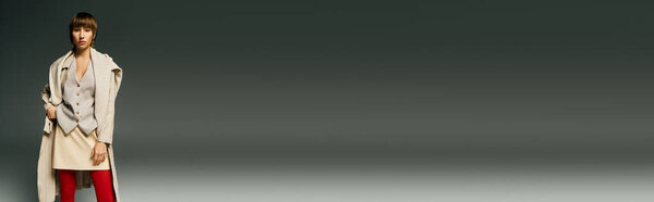 A stylish young woman in a white coat and striking red tights poses in a studio setting, exuding confidence and sophistication.