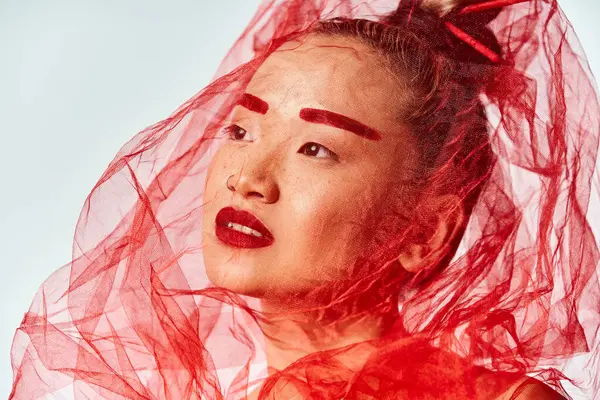 stock image Asian woman poses wearing a vibrant red veil.