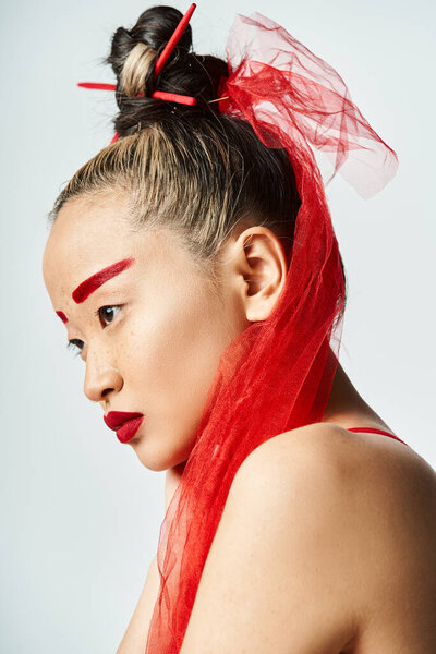 An attractive Asian woman with vibrant red hair and intense red makeup poses confidently.