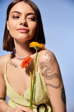 A young woman with brunette hair dressed in a yellow gown, holding a vibrant flower delicately. clipart